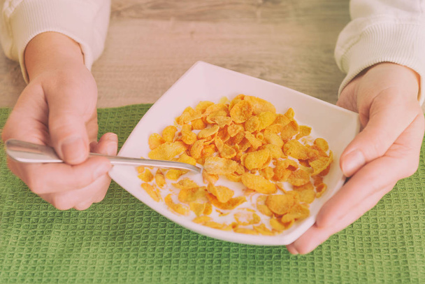 Female hands holding bowl with cornflakes and milk - Photo, Image