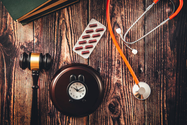 Gavel and stethoscope on wooden background, dark environment. - Photo, Image