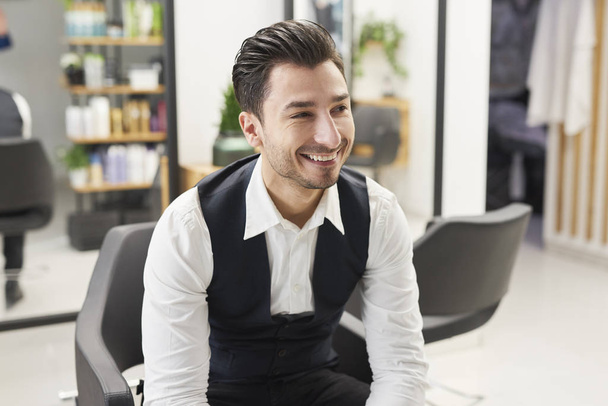 Smiling barber sitting in hair salon - Photo, Image