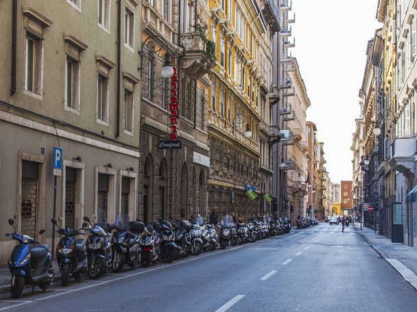 トリエステ,イタリア, 2019年8月5日.歴史ある街の美しい絵のような通り。歩道の近くに駐車している車やバイク - 写真・画像