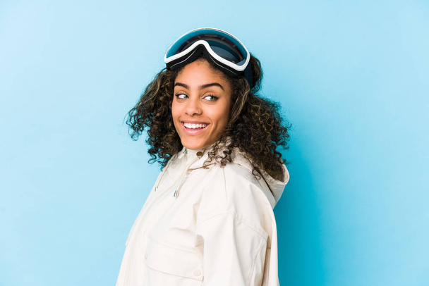 Joven esquiadora afroamericana aislada mira a un lado sonriente, alegre y agradable
. - Foto, imagen