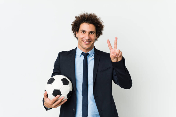 勝利のサインを示すボールを保持し、広く笑みを浮かべてサッカートレーナー. - 写真・画像