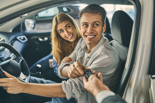 Smiling lovely couple receiving a key from a new car. - Foto, Imagen