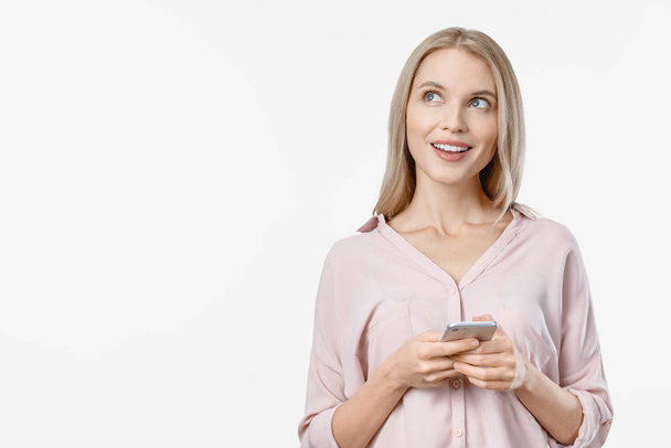 Houkutteleva ajattelu nuori blondi nainen poseeraa valkoisella taustalla matkapuhelimella
 - Valokuva, kuva