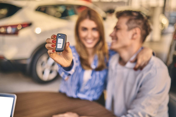 Happy cheerful girl getting a car key with handsome man in auto  - Foto, afbeelding