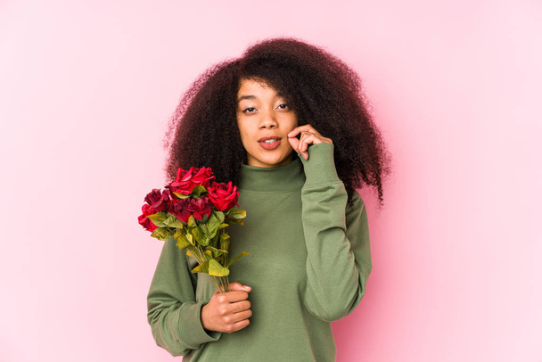 Молода афро-жінка тримає троянди ізольовані Молода афро-жінка тримає троянди з пальцями на губах тримаючи секрет
. - Фото, зображення