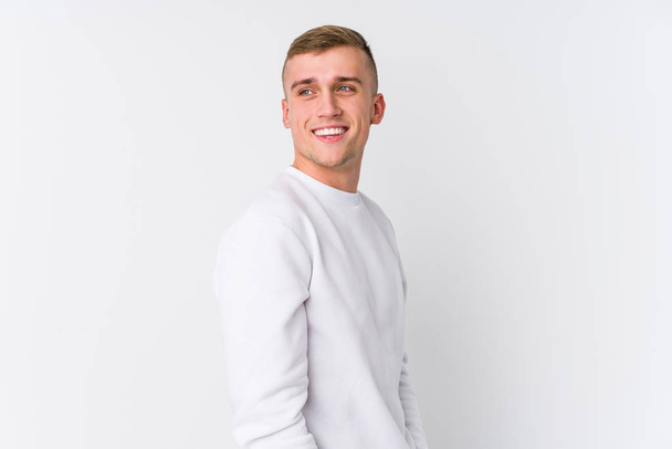 Jeune homme caucasien sur fond blanc regarde de côté souriant, gai et agréable
. - Photo, image
