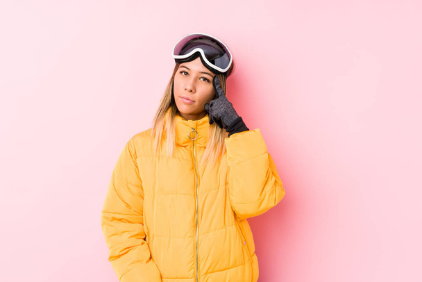 Young caucasian woman wearing a ski clothes in a pink background pointing temple with finger, thinking, focused on a task. - Foto, Imagen