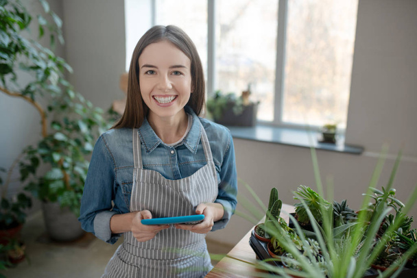 Smiling woman wearing apron holding a tablet - Foto, immagini