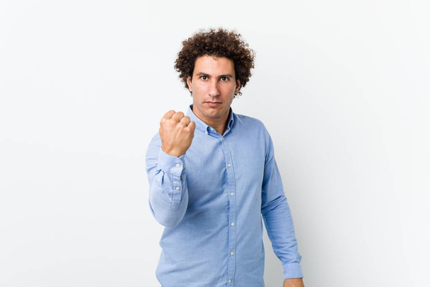 Jovem curly maduro homem vestindo uma camisa elegante mostrando punho para câmera, expressão facial agressiva
. - Foto, Imagem