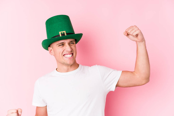 Young caucasian man celebrating saint patricks day raising fist after a victory, winner concept. - Photo, image