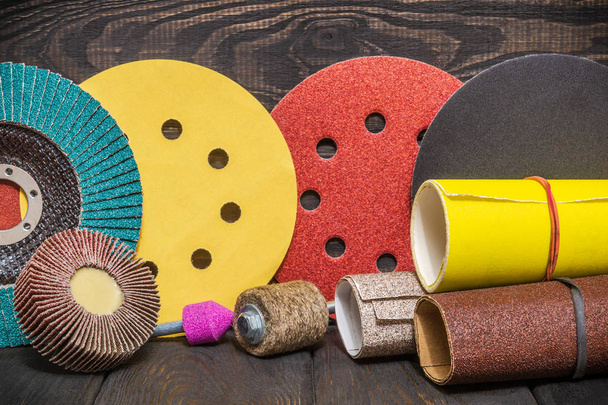 Gran conjunto de herramientas abrasivas y papel de lija multicolor sobre fondo negro vintage de madera
 - Foto, imagen