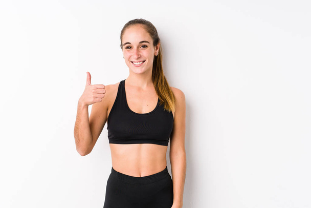 Young caucasian fitness woman posing in a white background smiling and raising thumb up - Photo, image