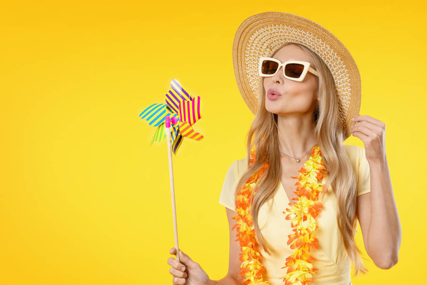 Attractive woman with beach accessories holding colorful toy on yellow background - Photo, Image