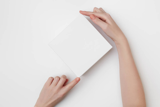 Burla de la caja de regalo blanco en las manos de las mujeres sobre el fondo blanco
 - Foto, Imagen