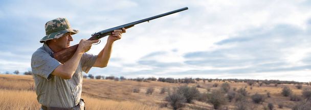 Uomo cacciatore in mimetizzazione con una pistola durante la caccia alla ricerca di uccelli selvatici o selvaggina. Stagione di caccia autunnale
. - Foto, immagini