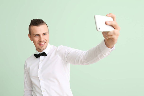 Knappe jongeman neemt selfie op kleur achtergrond - Foto, afbeelding