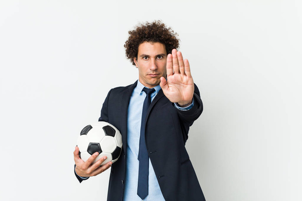 Trener piłki nożnej trzyma piłkę stojącą wyciągniętą ręką pokazując znak stopu, uniemożliwiając Ci. - Zdjęcie, obraz
