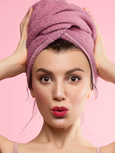 Beautiful young woman with clean perfect skin. Portrait of beauty model with natural nude make up and touching her face. Spa, skincare and wellness. Close up, pink background, copyspace and emotion - 写真・画像