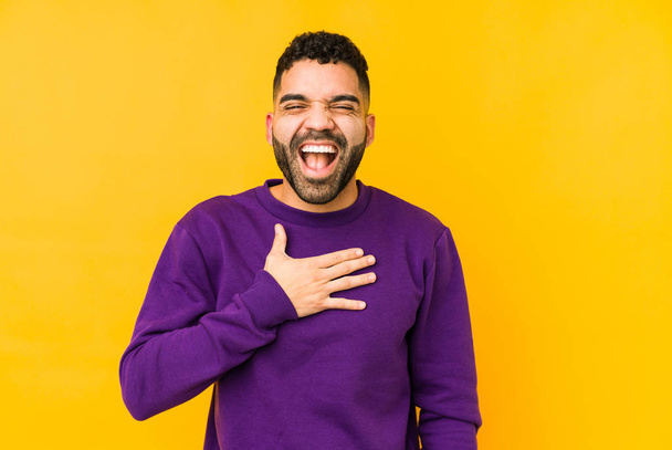 Jonge gemengde ras Arabische man geïsoleerde lacht luid houden hand op de borst. - Foto, afbeelding