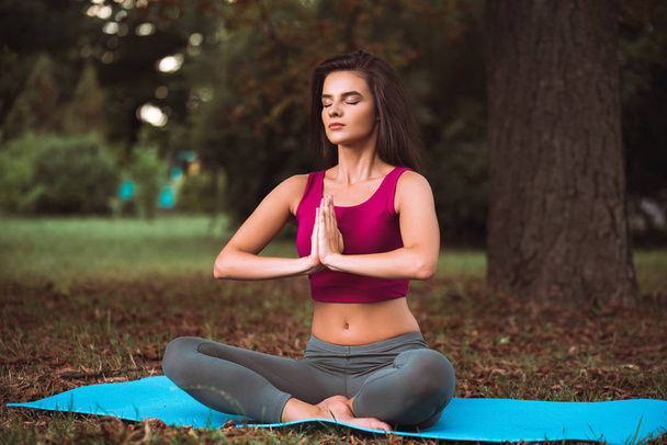 young brunette in sportswear is meditating outdoors  - Foto, Imagem