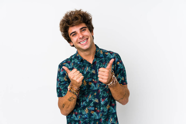 Молодой кавказский мужчина в цветочной футболке, изолированный, поднимающий оба больших пальца вверх, улыбающийся и уверенный в себе
. - Фото, изображение