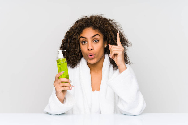 Young african american woman holding an aloe vera having some great idea, concept of creativity. - 写真・画像