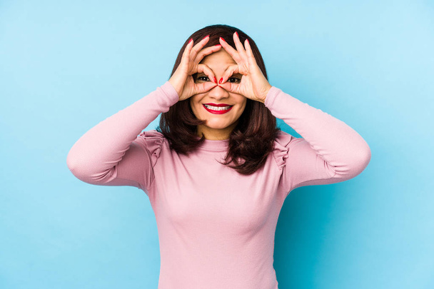 Middle age latin woman isolated showing okay sign over eyes - Photo, Image