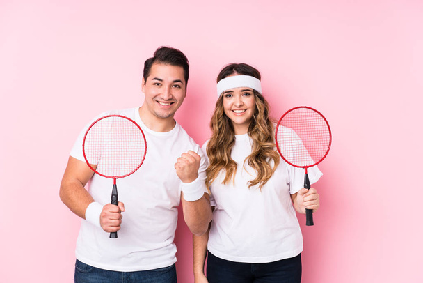Young couple playing badminton isolated happy, smiling and cheerful. - Photo, Image