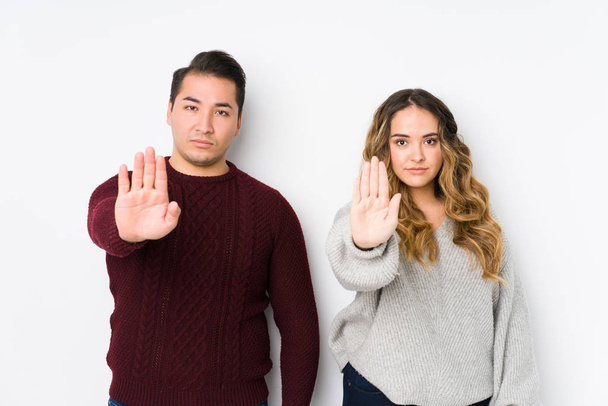 Nuori pari poseeraa valkoisella taustalla seisoo ojennetulla kädellä osoittaa stop-merkki, estää sinua
. - Valokuva, kuva