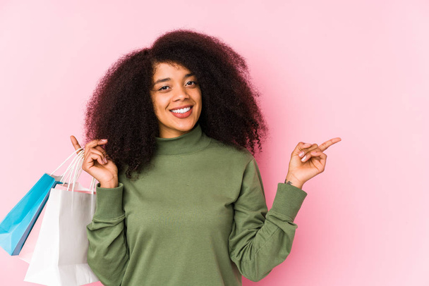 Young afro woman shopping isolated Young afro woman buying isolaYoung afro woman holding a roses isolated smiling and pointing aside, showing something at blank space. - Foto, Imagen