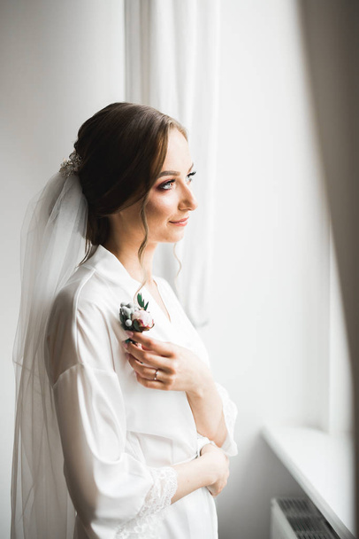 Beautiful bride wearing fashion wedding dress with feathers with luxury delight make-up and hairstyle, studio indoor photo shoot - Valokuva, kuva