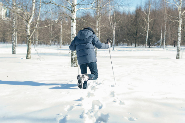 Boy teenager on skis in a park of winter snow drifts - Fotó, kép