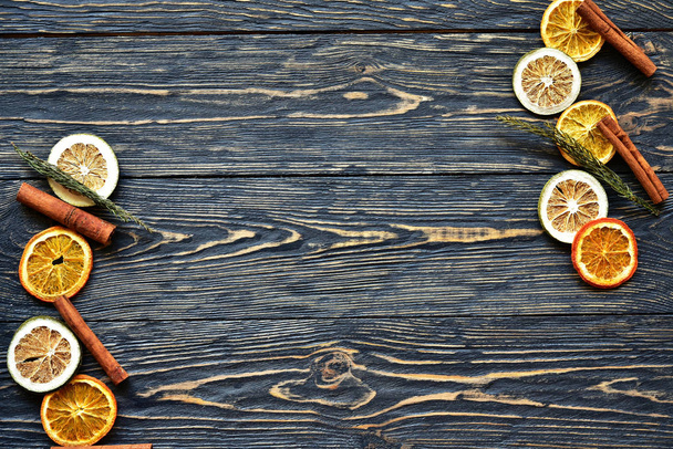 Fette essiccate di arancia e lime e bastoncini di cannella su uno sfondo di legno scuro. Luce naturale. Vista dall'alto
. - Foto, immagini