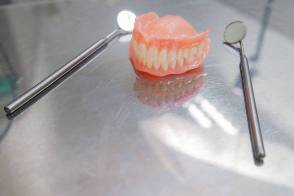 Набор зубных протезов и стоматологических инструментов. Закройте Зубы и зубное зеркало. Диагностика и копейка
 - Фото, изображение