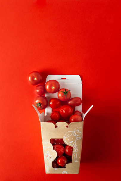 Sladké cherry rajčata v papar vyjmout krabici na oranžové červené pozadí s kopírovacím prostorem - Fotografie, Obrázek