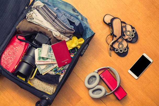 Suitcase full of clothes on the floor. Travel concept - Photo, image