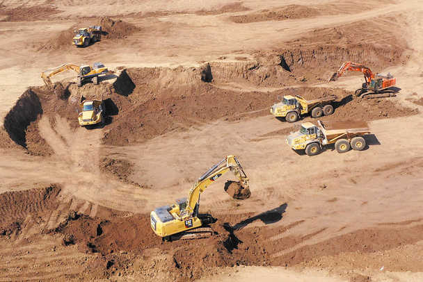 Kazıcıların eklemli nakliye kamyonlarına toprak yüklediği hava görüntüsü - Fotoğraf, Görsel