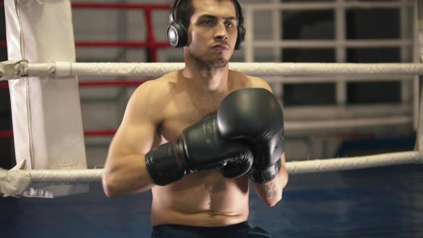 Boxer mit Handschuhen und Kopfhörern auf dem Ring - Foto, Bild