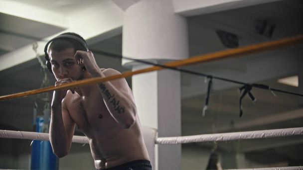 Um homem boxeador a treinar os seus golpes no ringue
 - Foto, Imagem