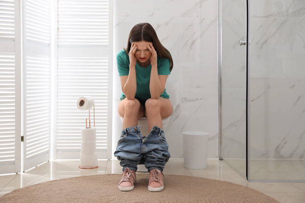 Woman suffering from hemorrhoid on toilet bowl in rest room - Φωτογραφία, εικόνα