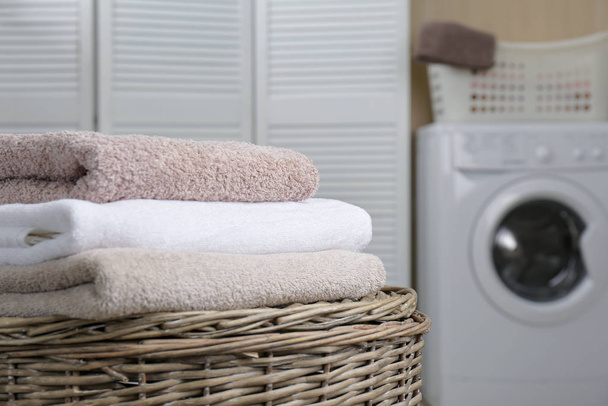 Fresh towels on wicker basket in laundry room. Space for text - Φωτογραφία, εικόνα