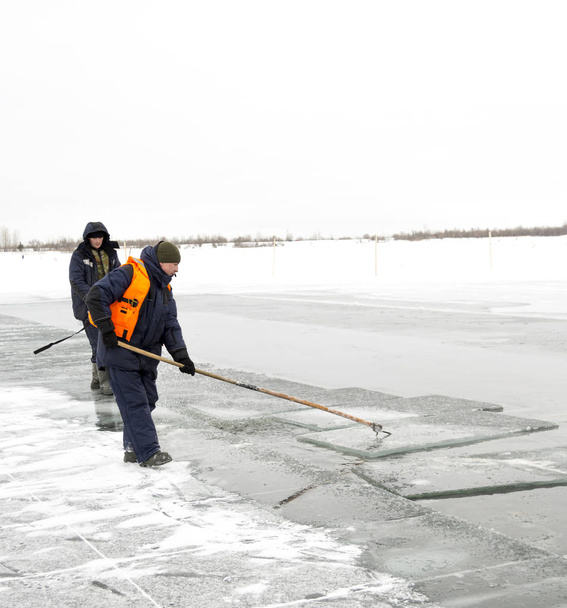 Balsas para trabajadores bloques de hielo a lo largo de un canal tallado en un lago congelado
 - Foto, imagen
