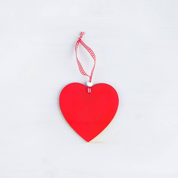 One heart of love on a ribbon on a white wooden background. The concept of love, romance and Valentine's Day. Square. - Фото, зображення