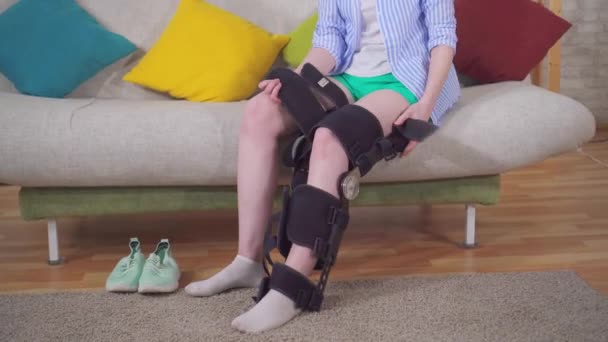 young woman removes the orthosis from her leg after an injury and walks - Filmati, video