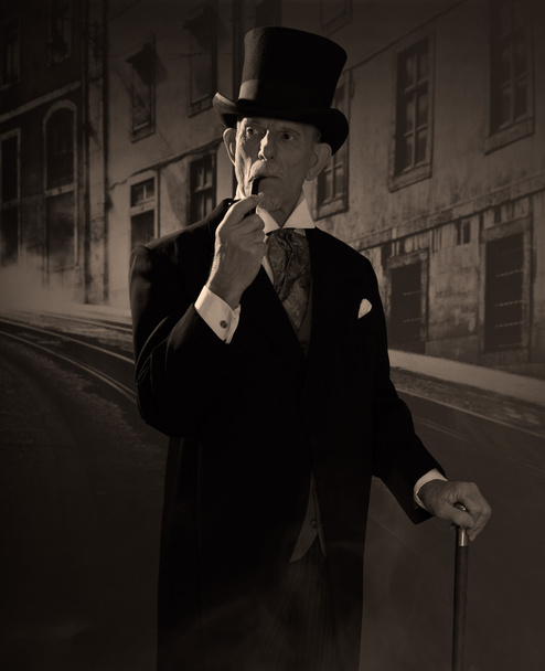 Mann um 1900, der Pfeife raucht und schwarzen Hut und Mantel trägt. Das ist nicht der Fall. - Foto, Bild