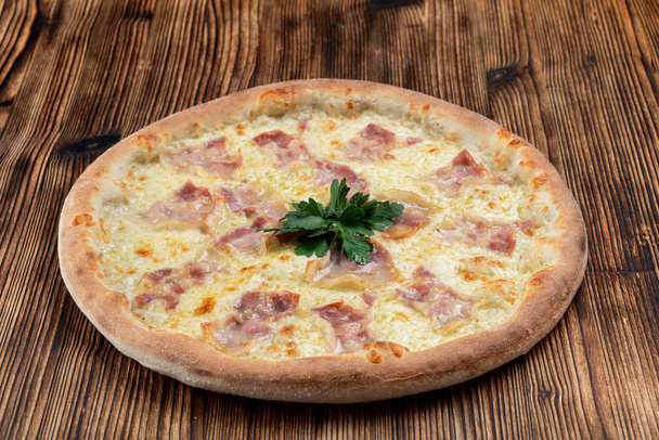 Pizza italiana caliente con queso derretido y tiras de tocino sobre fondo de madera
  - Foto, imagen