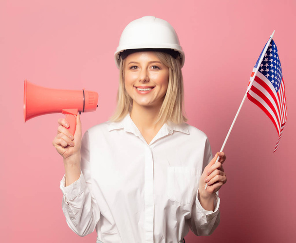 Mujer con camisa blanca y casco sostiene altavoz y bandera de EE.UU.
  - Foto, Imagen