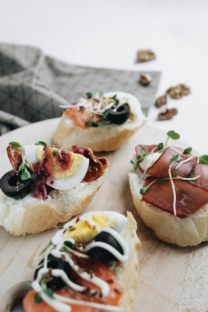 Delicious fresh bruschettas with eggs, salmon, olives and meat , traditional Italian cuisine, ingredients on white  table - Foto, Bild