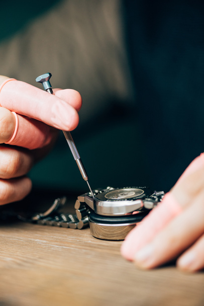 Kol saati ve tornavidayla çalışan lateks parmak uçlu saat yapımcısının kırpılmış görüntüsü - Fotoğraf, Görsel